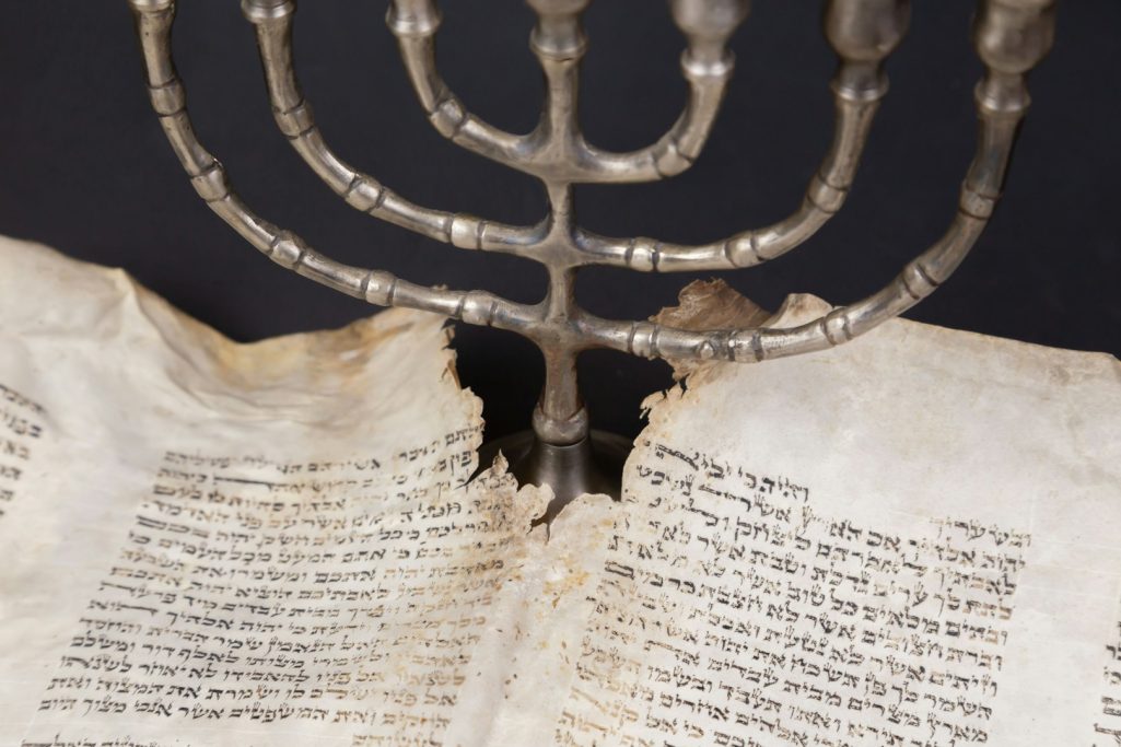 Menorah en métal au-dessus d'un livre ancien aux pages vieillies.